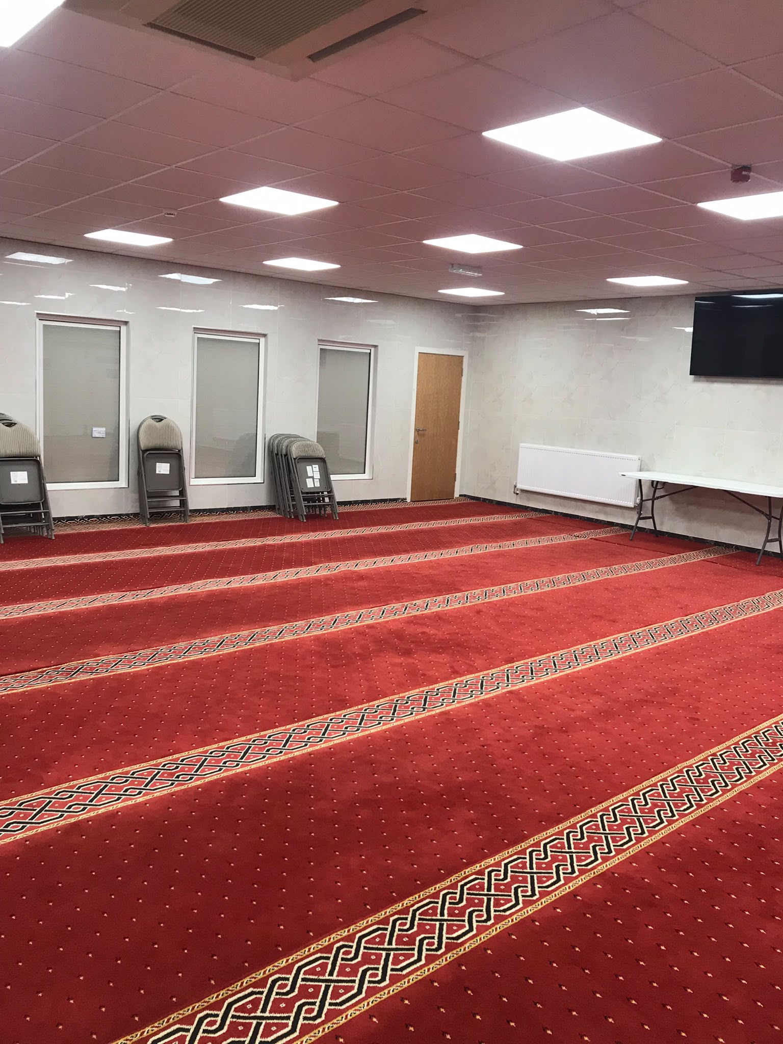 Prayer room with red carpet and rows for salah