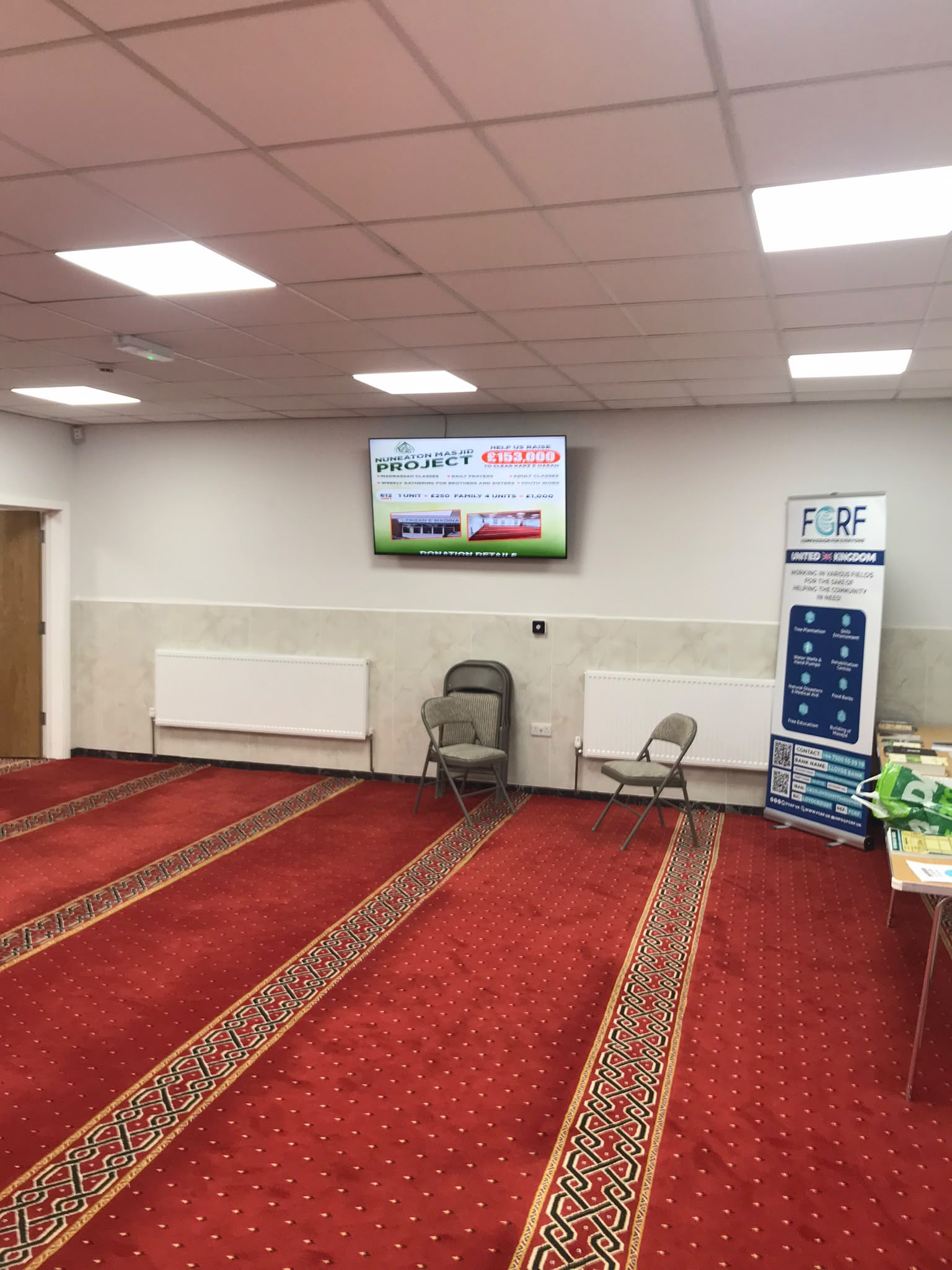 Prayer hall with red carpet and a wall display